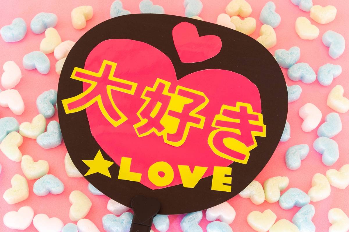Brown fan with pink heart and yellow text reading Love in Japanese and English.