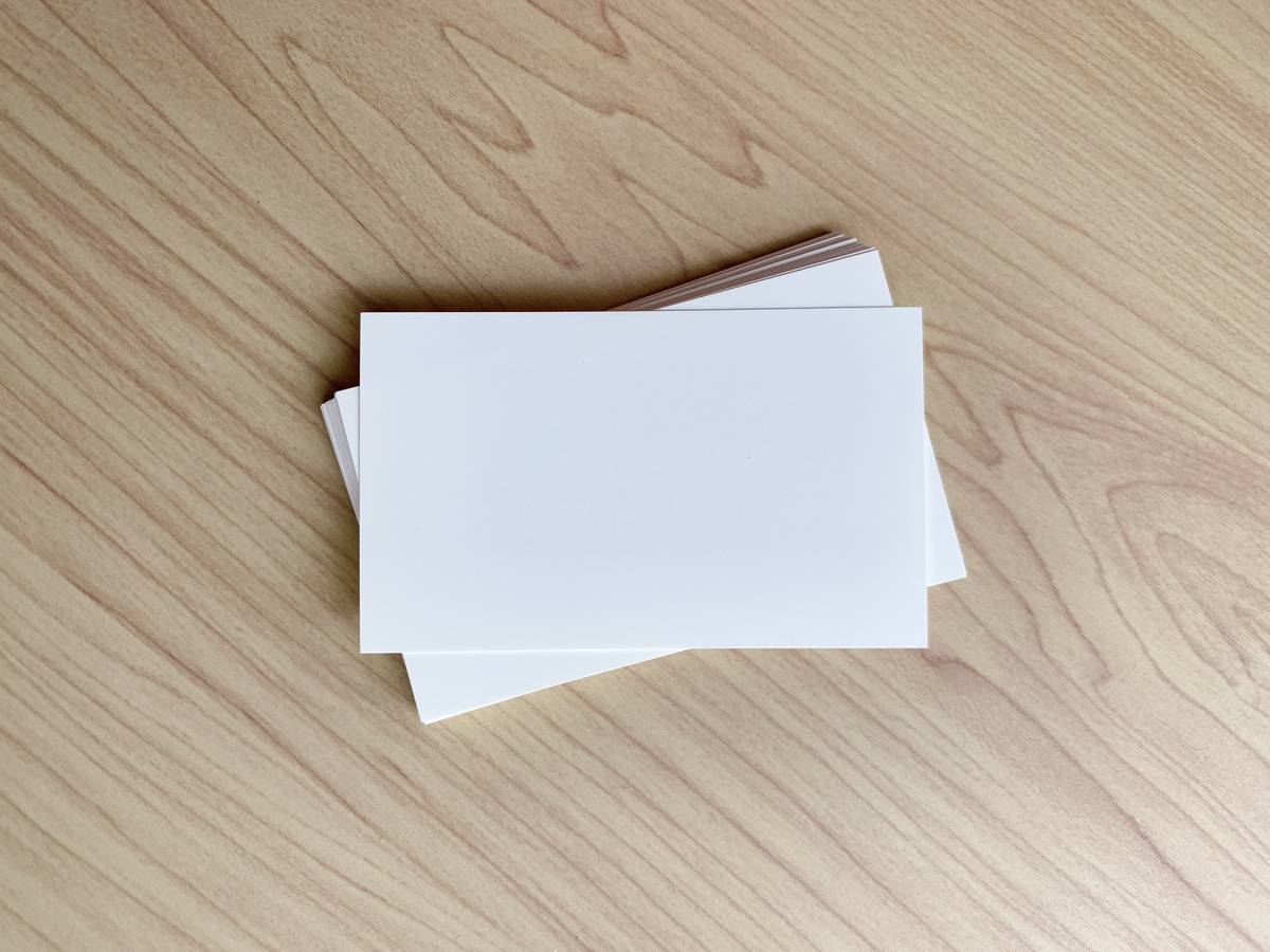 A stack of blank white business cards on a light wooden surface.