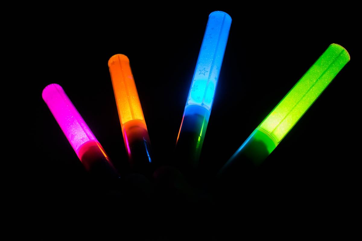 Four glowing light sticks in pink, orange, blue, and green.