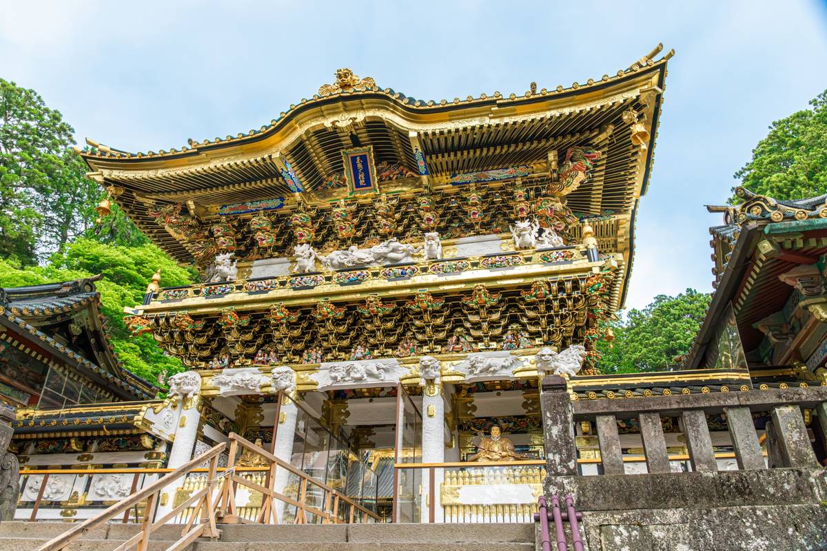 Highly ornate, gilded Japanese temple gate with multiple tiers and intricate carvings