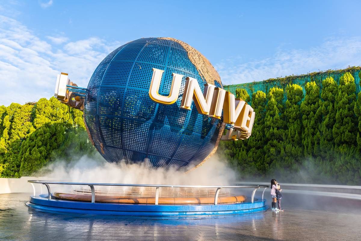The iconic blue Universal Studios globe with "UNIVERSAL" text, surrounded by mist, and a small person standing nearby.