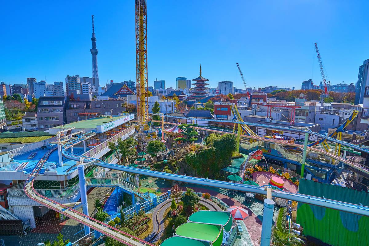 Amusement park with roller coasters and a drop tower, with Tokyo Skytree and a pagoda in the background.