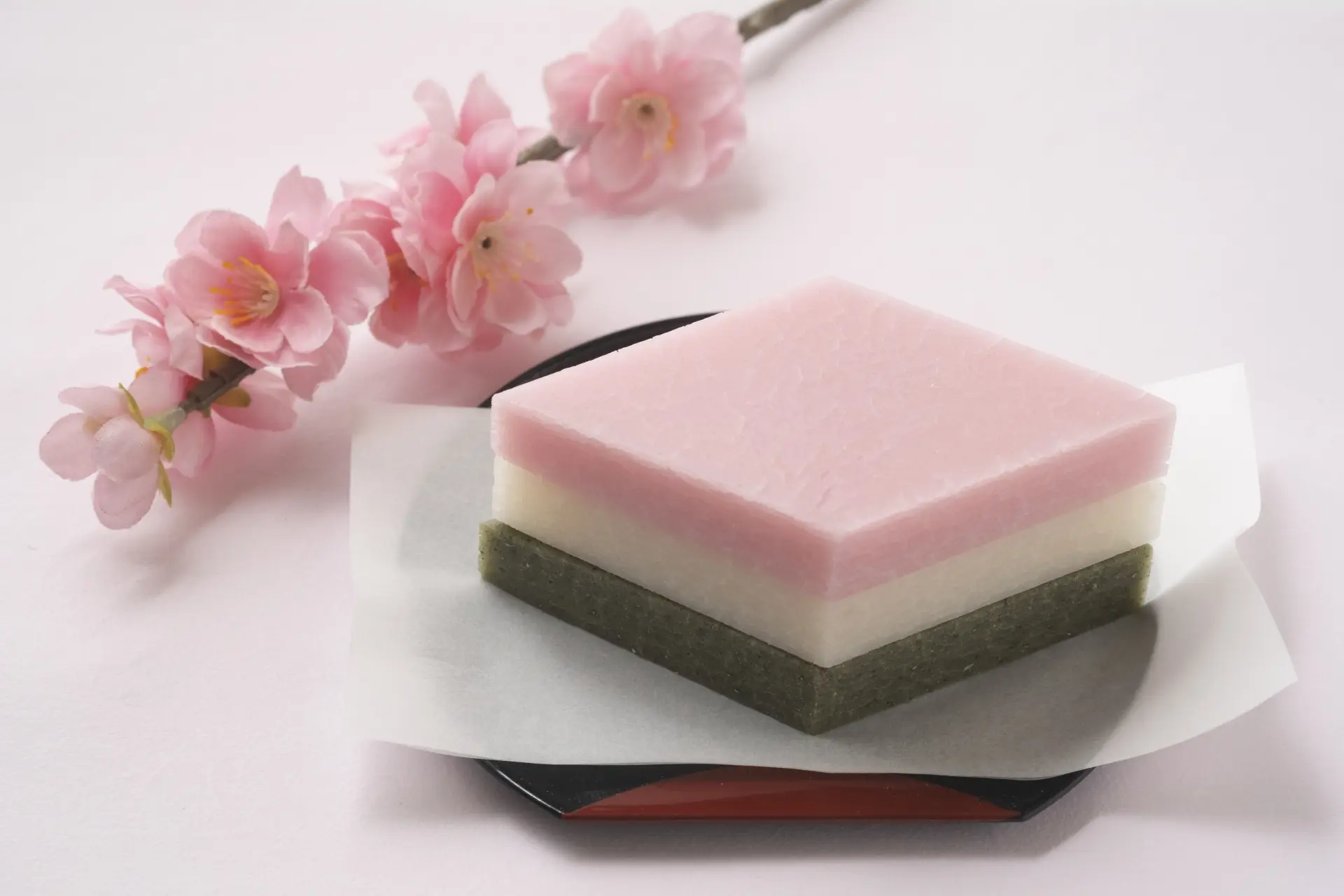 Hishimochi, a pink, white, and green layered sweet, with pink cherry blossoms.