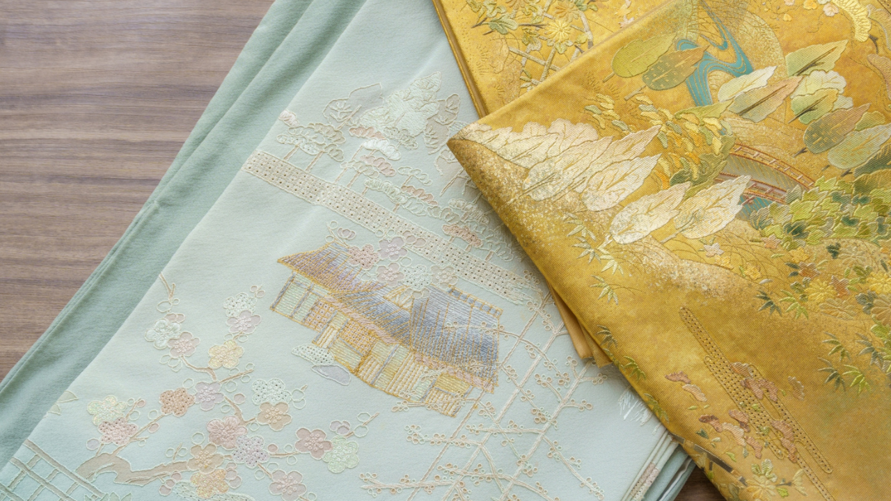 Japanese embroidery depicting a serene landscape with a winding river, arched bridge, traditional house