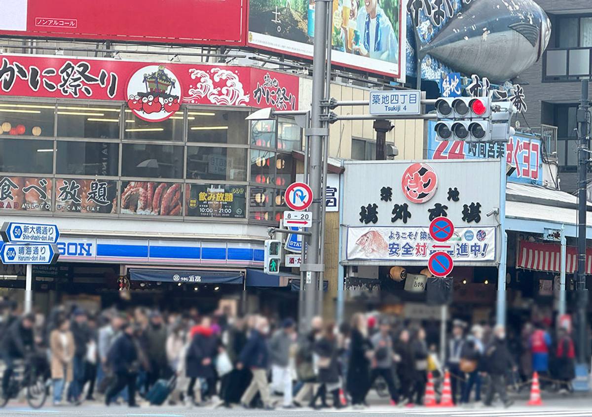 A busy street in Japan with pedestrians, a Crab Festival restaurant, and a large tuna sculpture on a building.