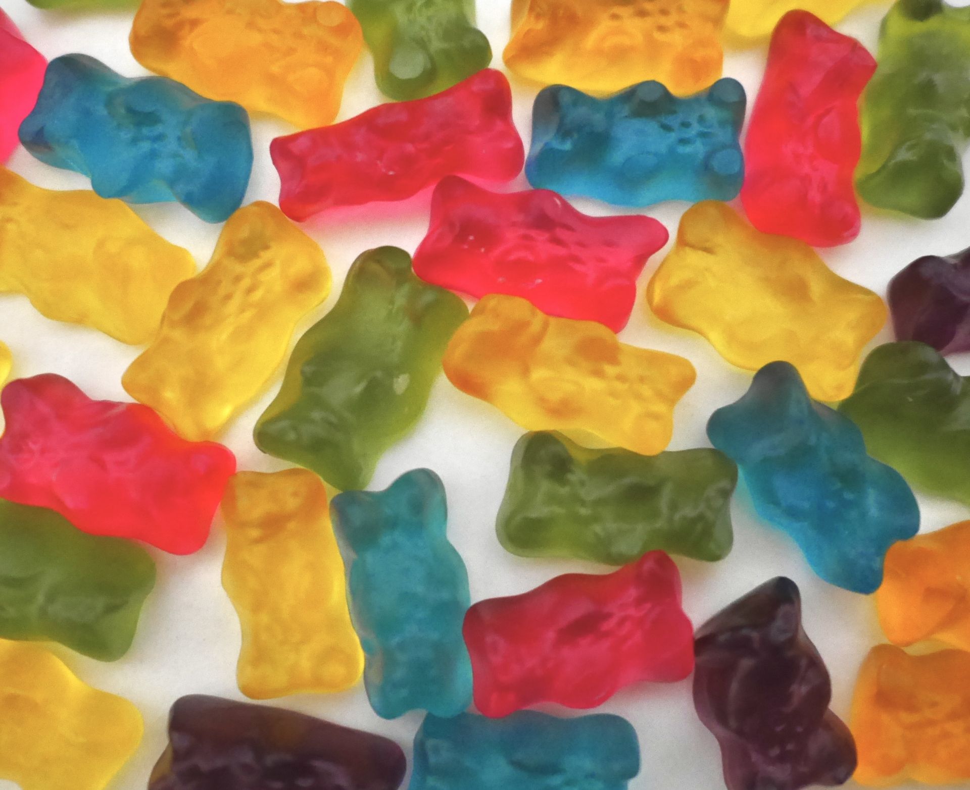 A pile of colorful gummy candies on a white surface.