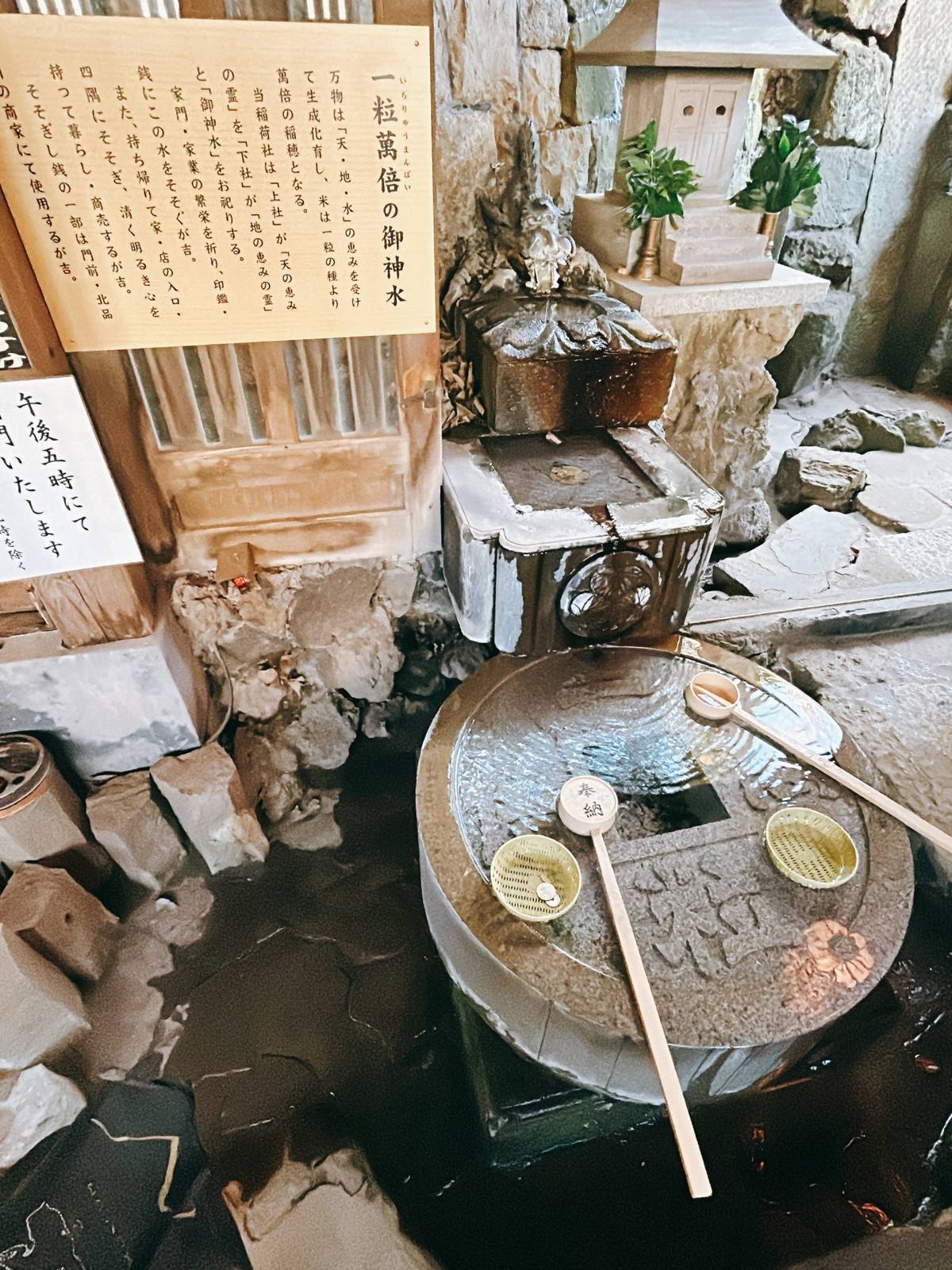 A stone purification basin at a Japanese shrine, with ladles, coins, and water flowing from a dragon spout.