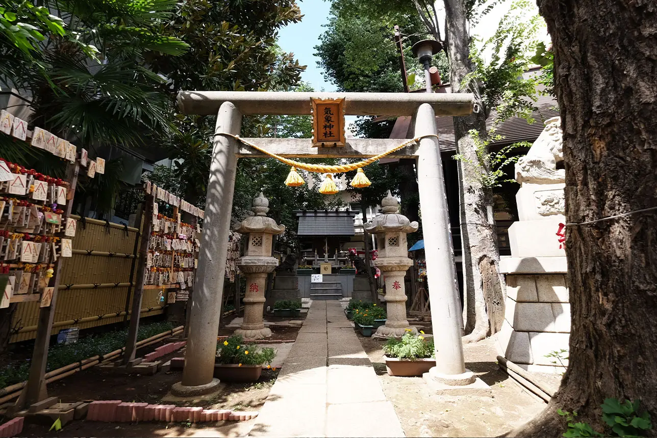 A stone torii gate with a shimenawa rope marks the entrance to a Japanese shrine