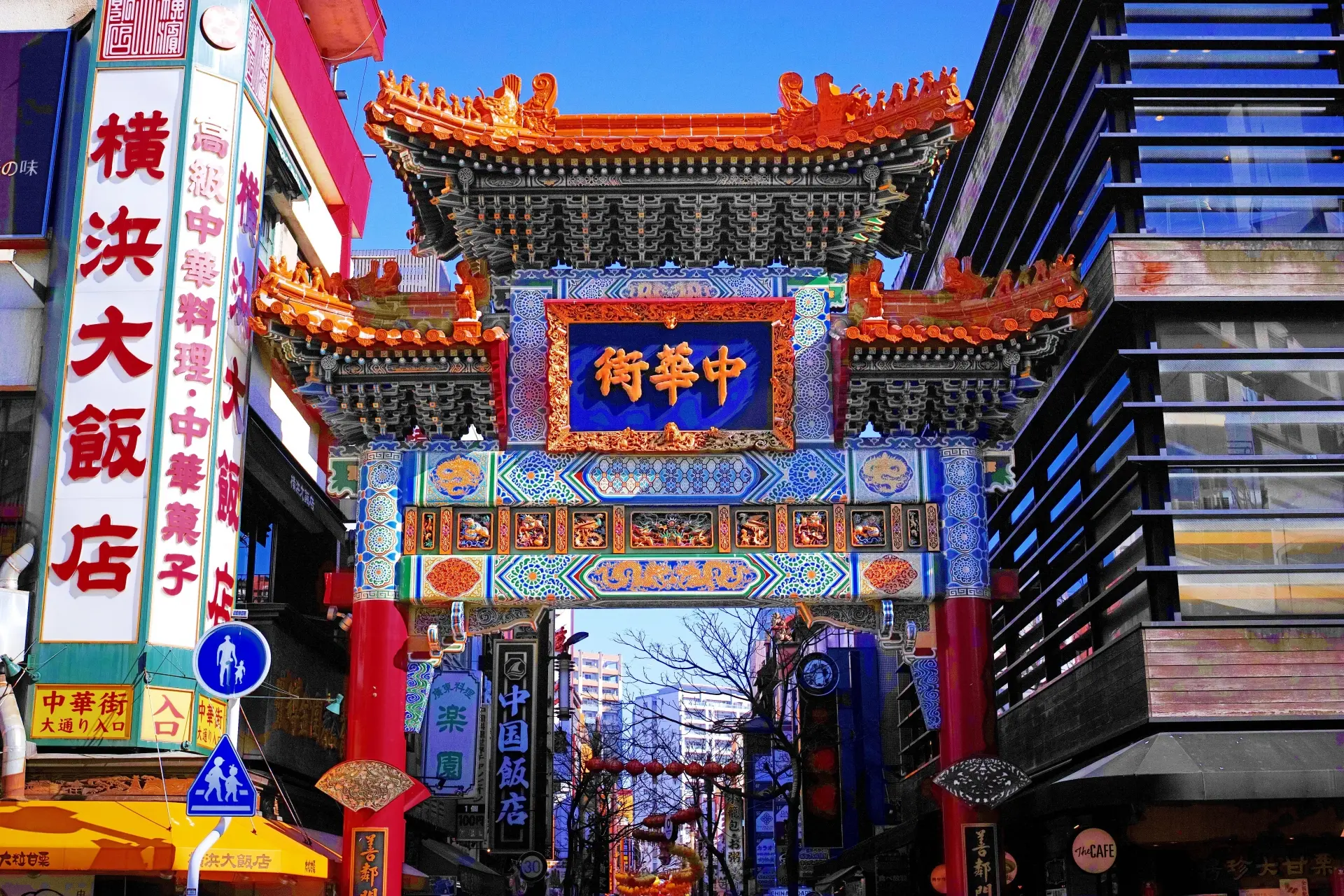 The ornate, colorful main gate of Yokohama Chinatown under a clear blue sky.