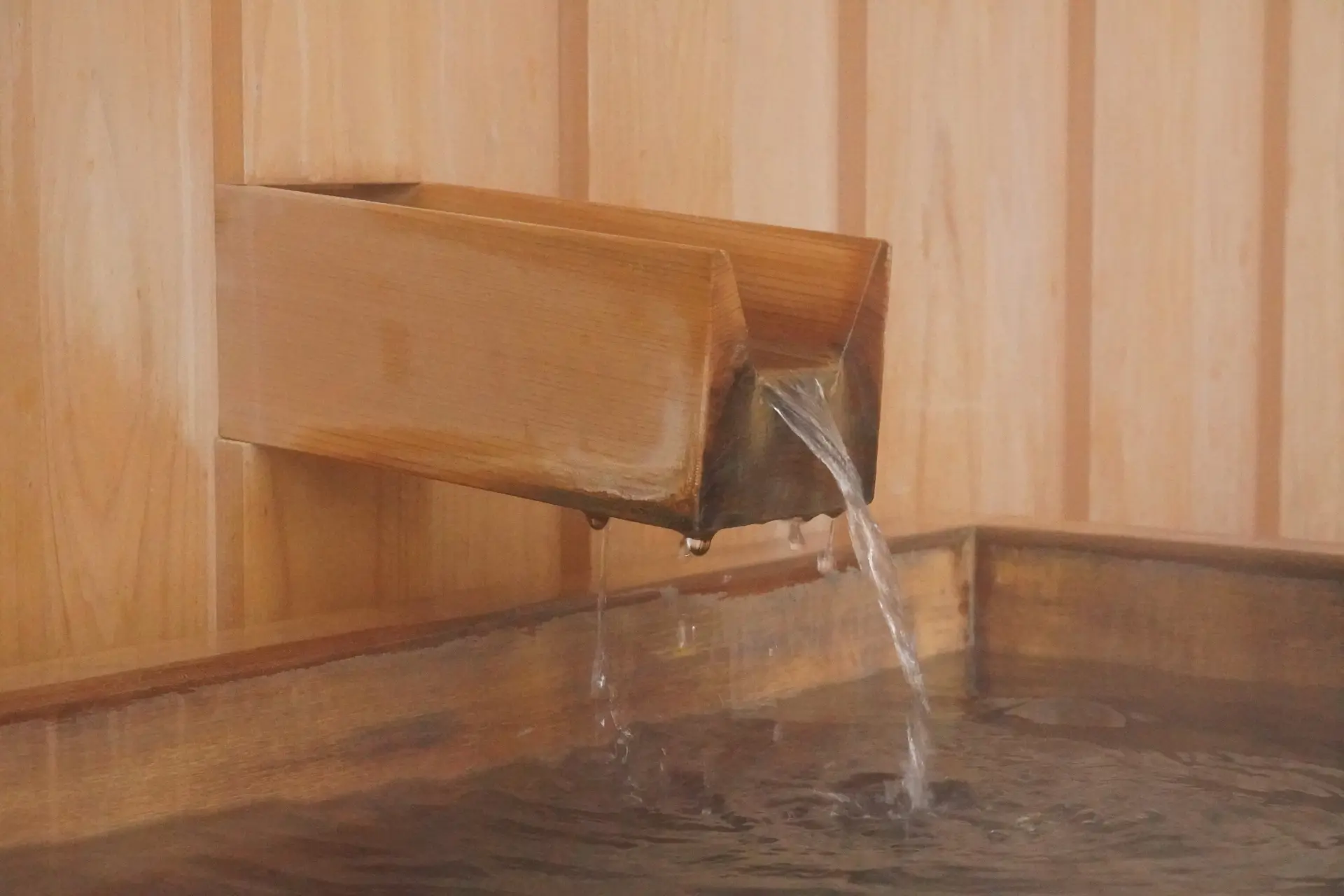 Wooden spout pouring water into a wooden tub.