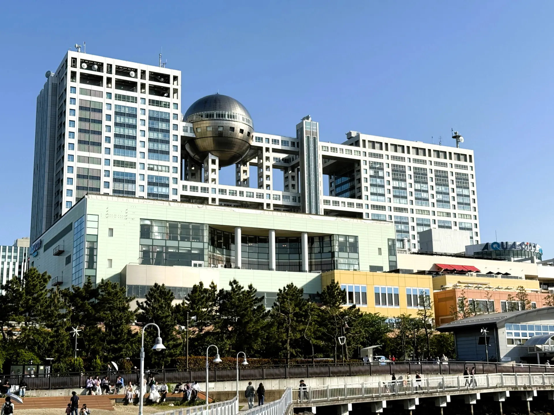 The Fuji TV Building in Tokyo, a modern structure with a large silver sphere suspended between two high-rise sections