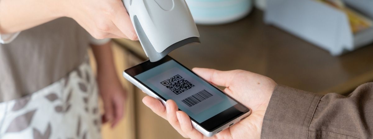 A scanner reading a QR code and barcode from a smartphone screen.