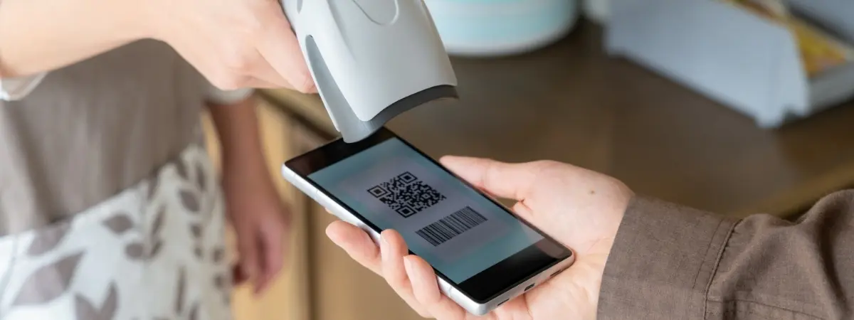 A scanner reading a QR code and barcode from a smartphone screen.