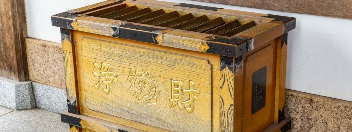 A wooden Japanese offering box with golden characters.