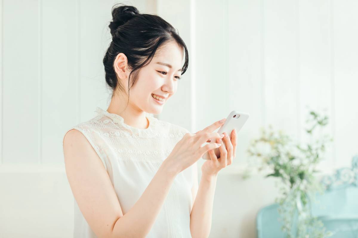 Smiling young woman looking at and interacting with a smartphone.