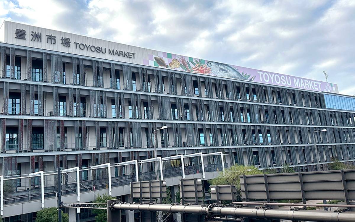 The modern Toyosu Market building with its prominent sign and colorful mural.