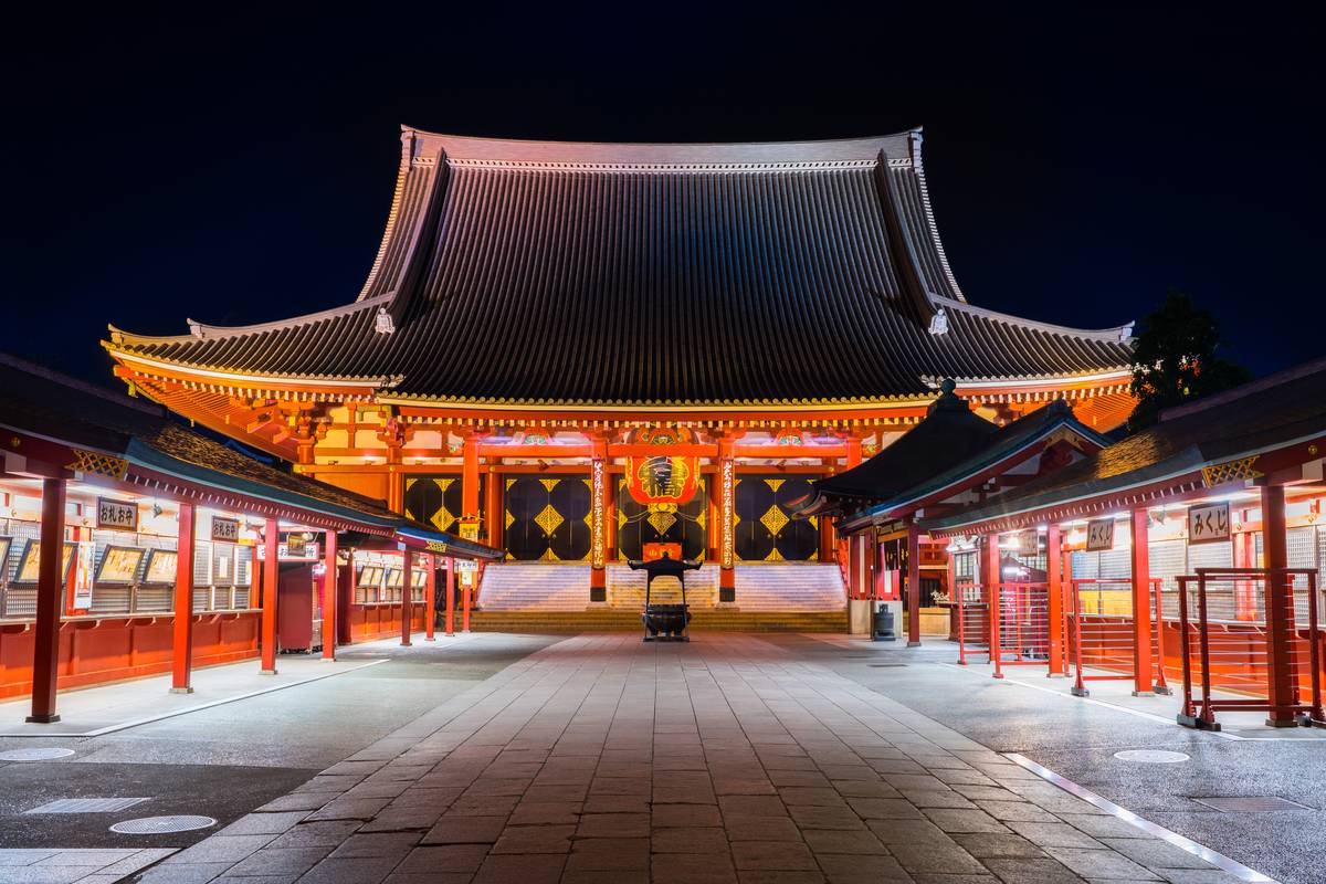 Illuminated red and black Japanese temple at night.