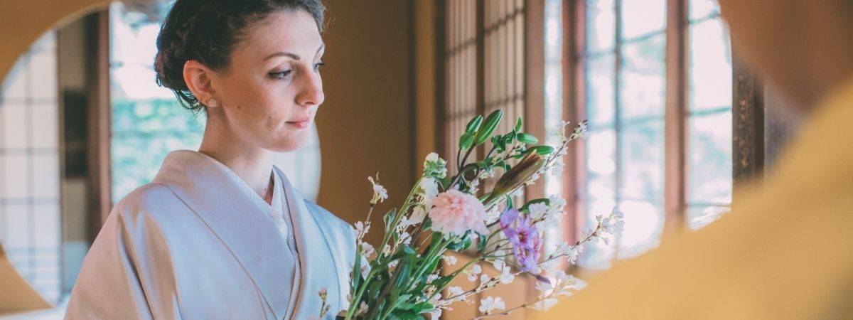 Woman in a light kimono holding a bouquet of flowers.