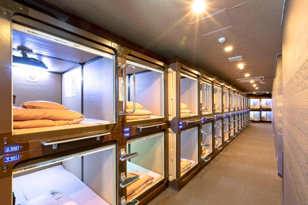 A hallway in a capsule hotel lined with rows of stacked sleeping pods.