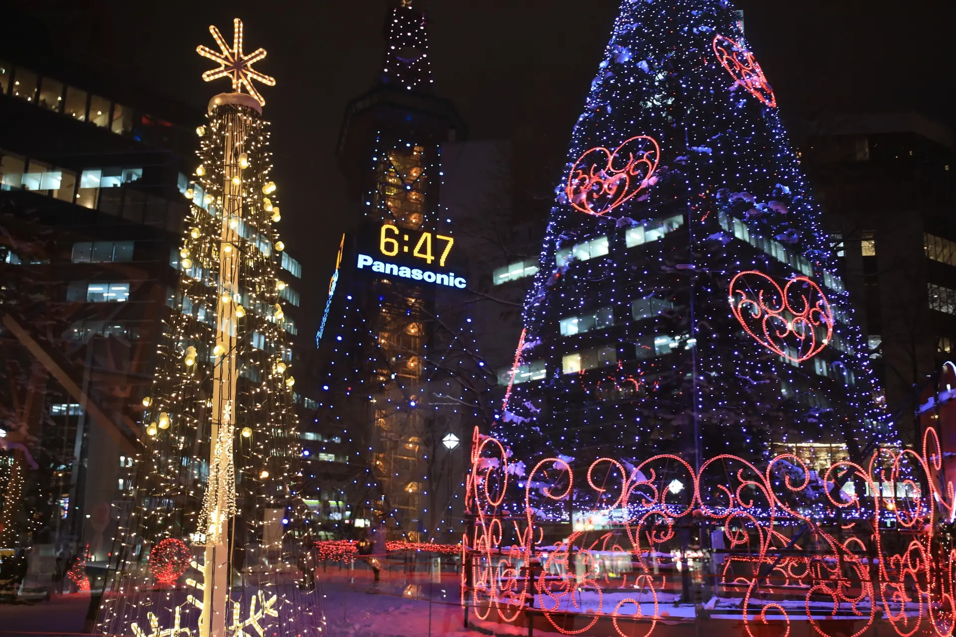 Two large Christmas trees brightly lit at night