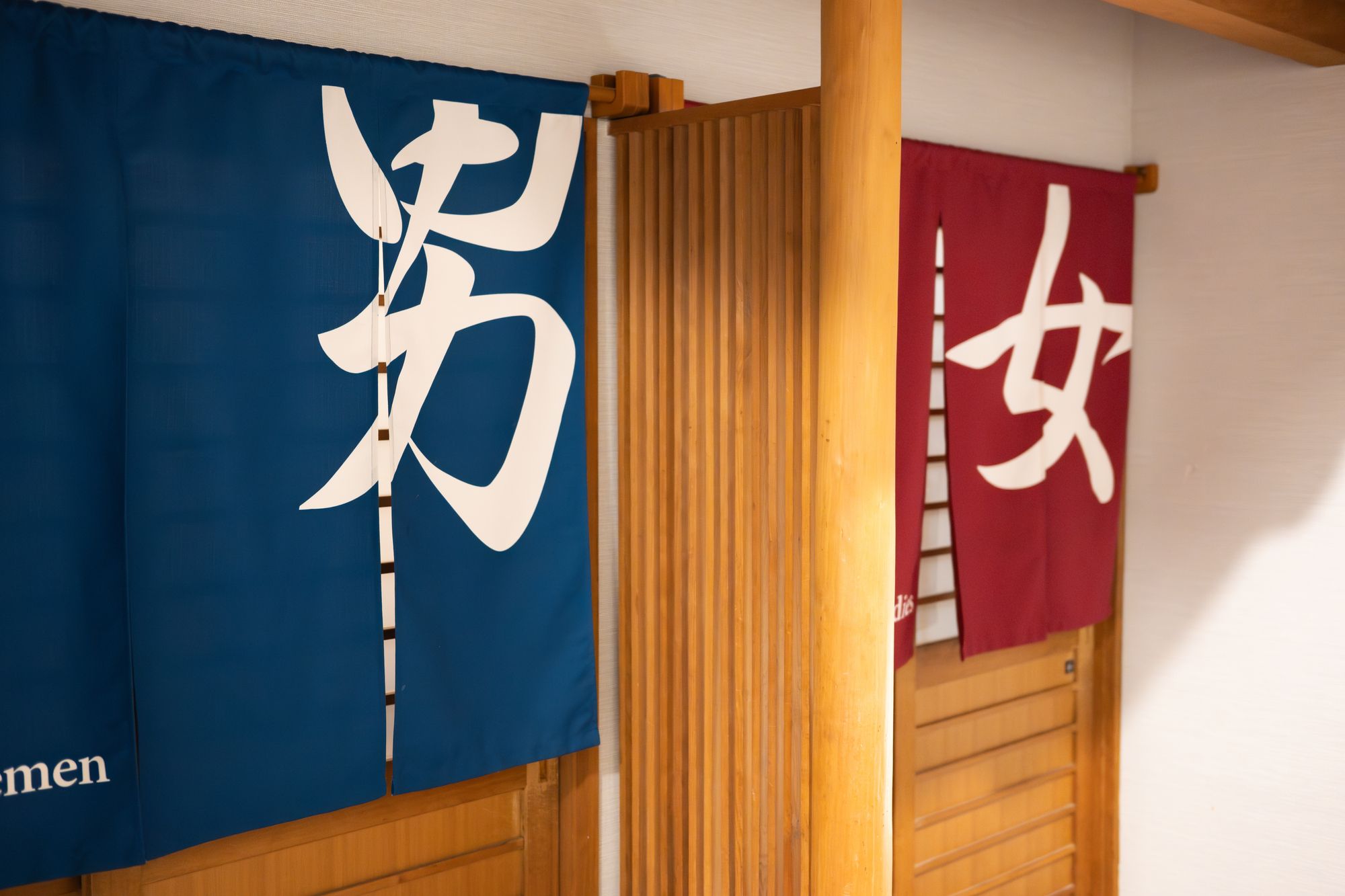 Japanese noren curtains: blue with "man" kanji and "men" in English, red with "woman" kanji.