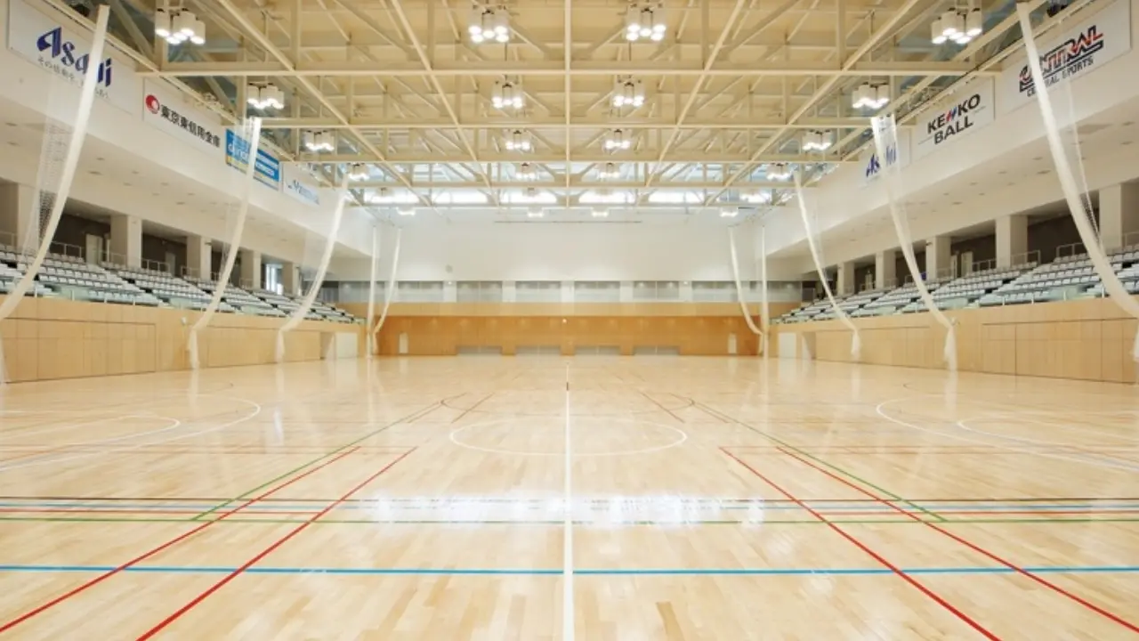 a large indoor basketball court with a wooden floor and bleachers .