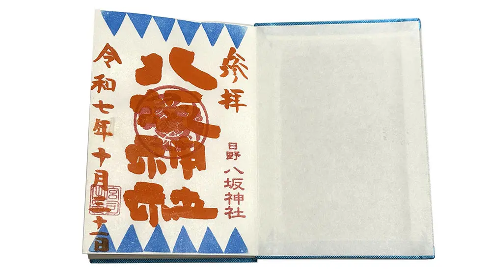 An open book showing a left page with red and black Japanese calligraphy and a blue triangular pattern