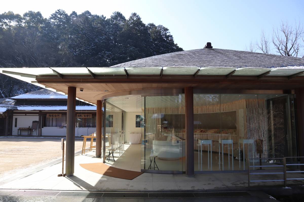 A modern building with a curved glass and wood facade, next to a traditional building