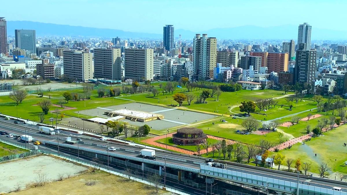 Elevated view of a city with a large green park, a highway, and a dense skyline.