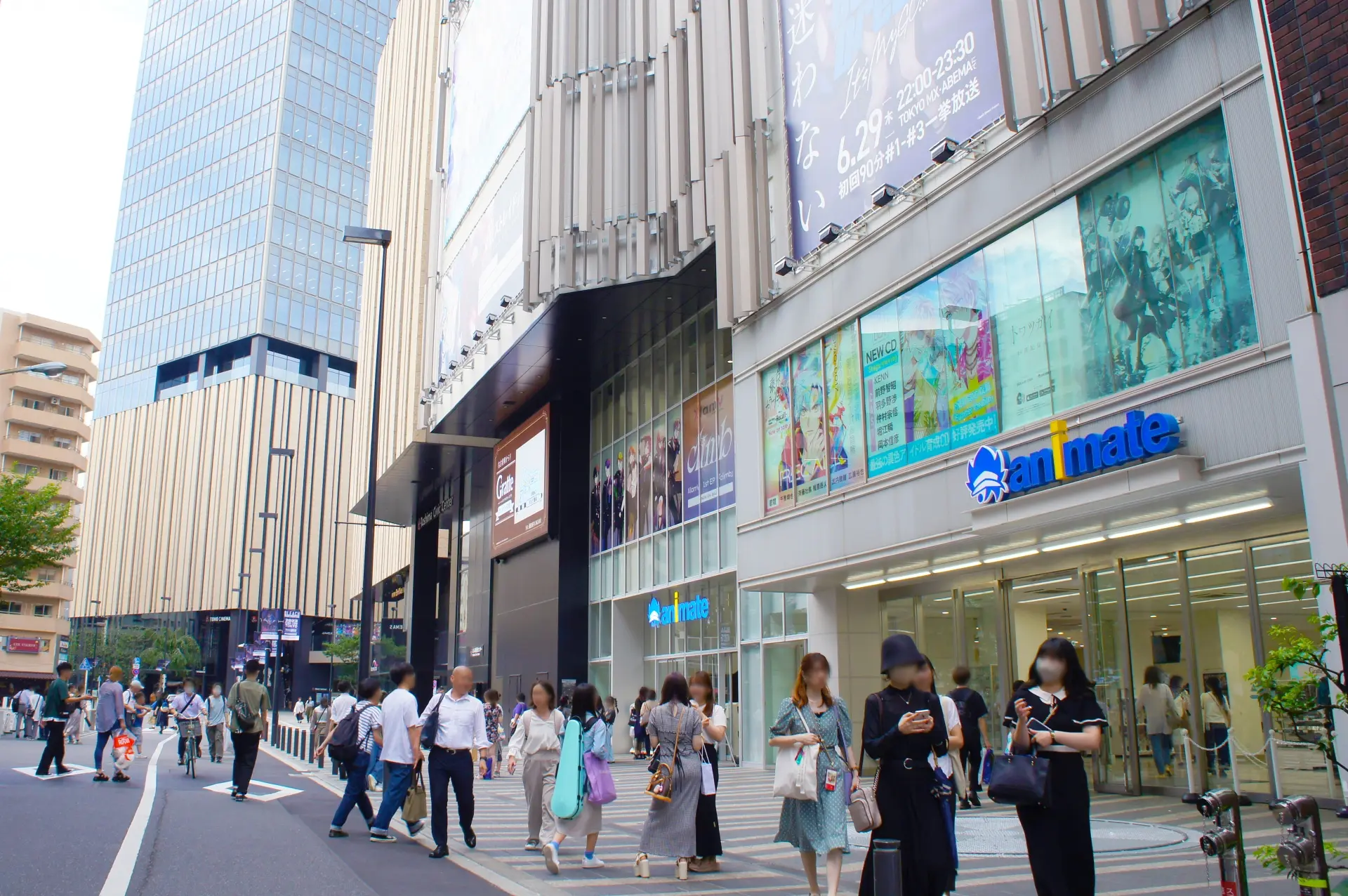A busy urban street scene with pedestrians walking past modern buildings, including an Animate store.