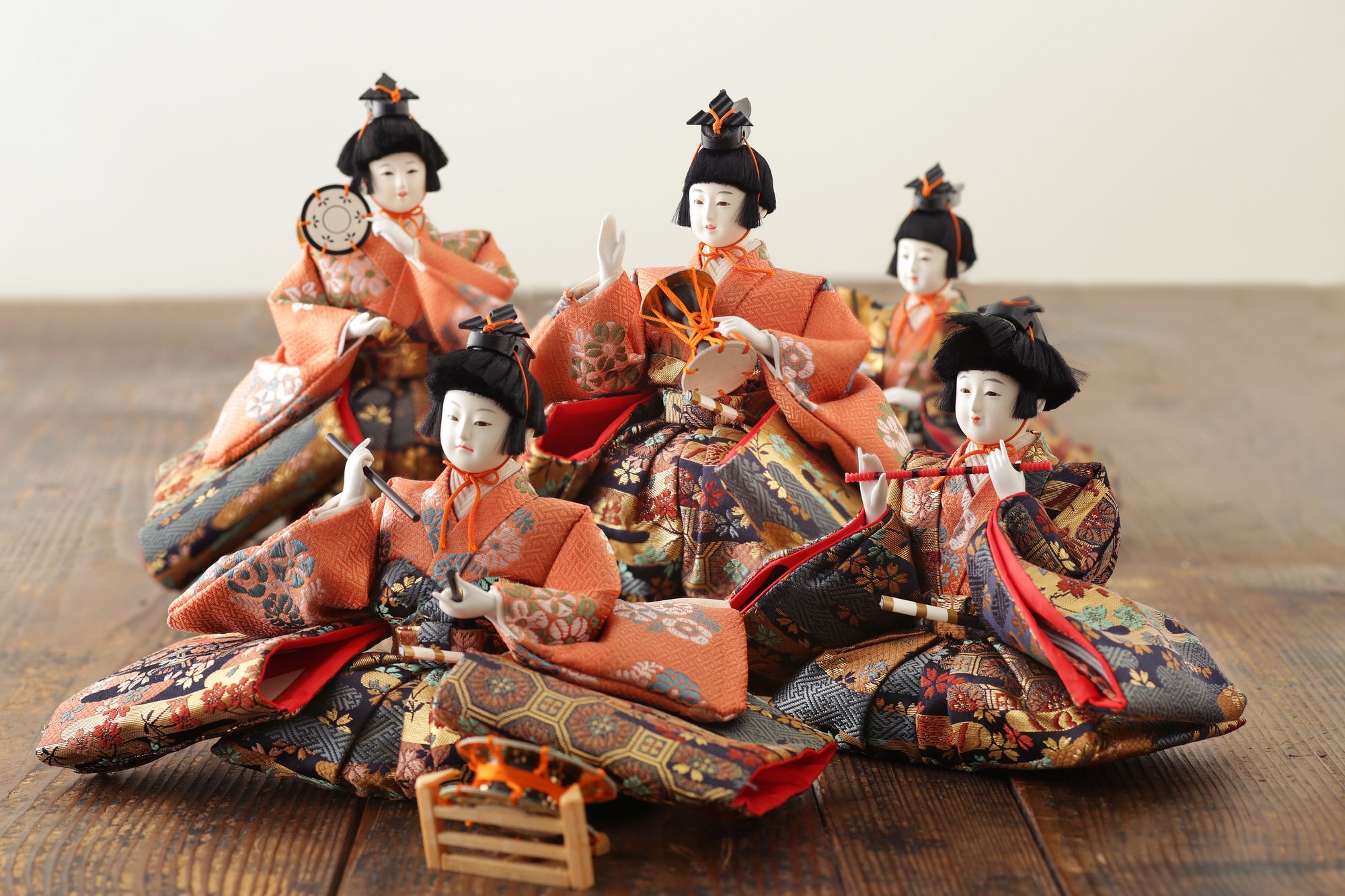 Five Hina dolls in ornate kimonos, some holding miniature musical instruments.