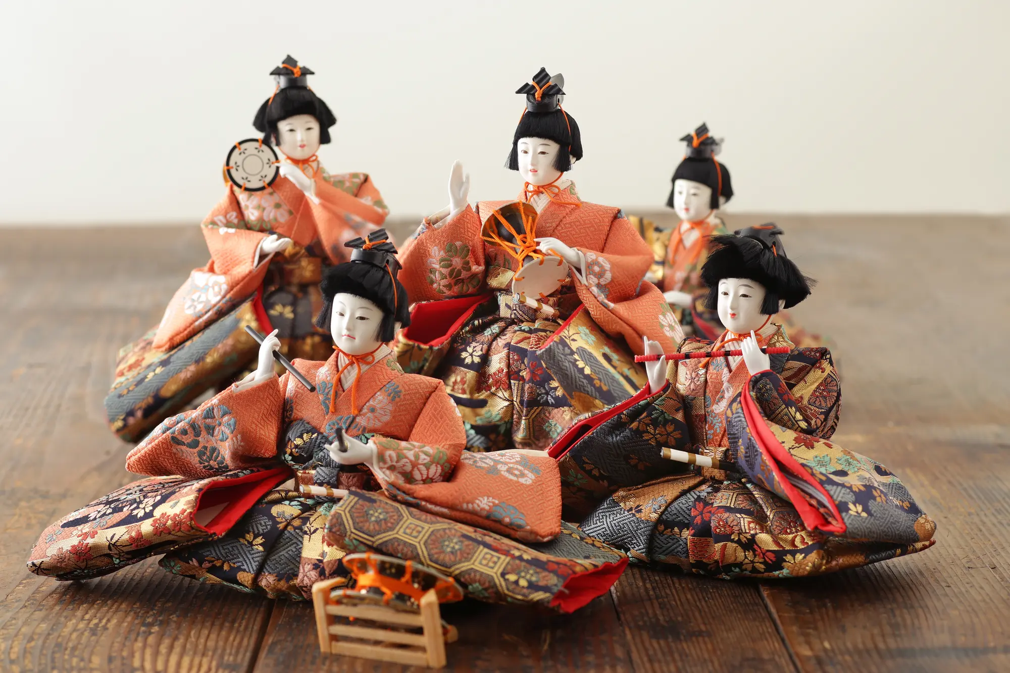 Five Hina dolls in ornate kimonos, some holding miniature musical instruments.