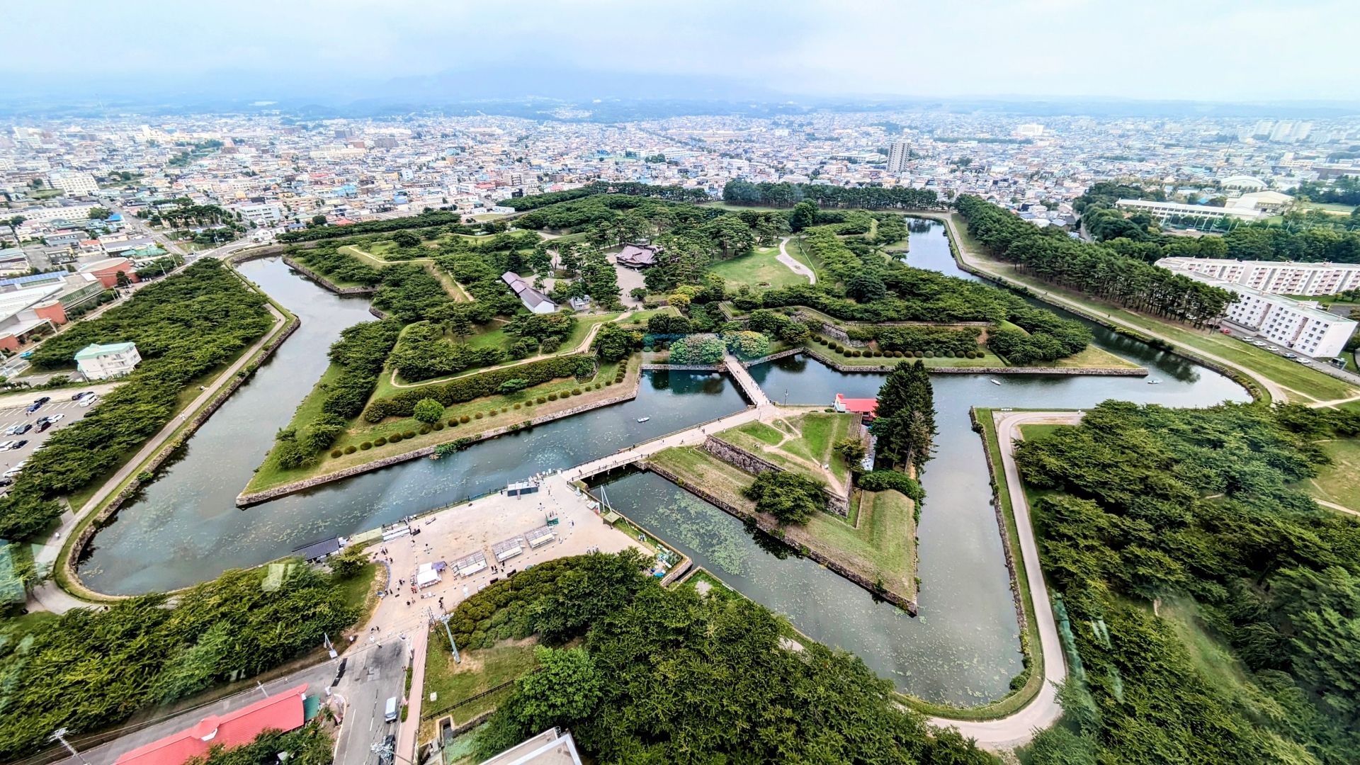 Aerial view of a star-shaped fort with a wide moat and green grounds, bordered by a city.