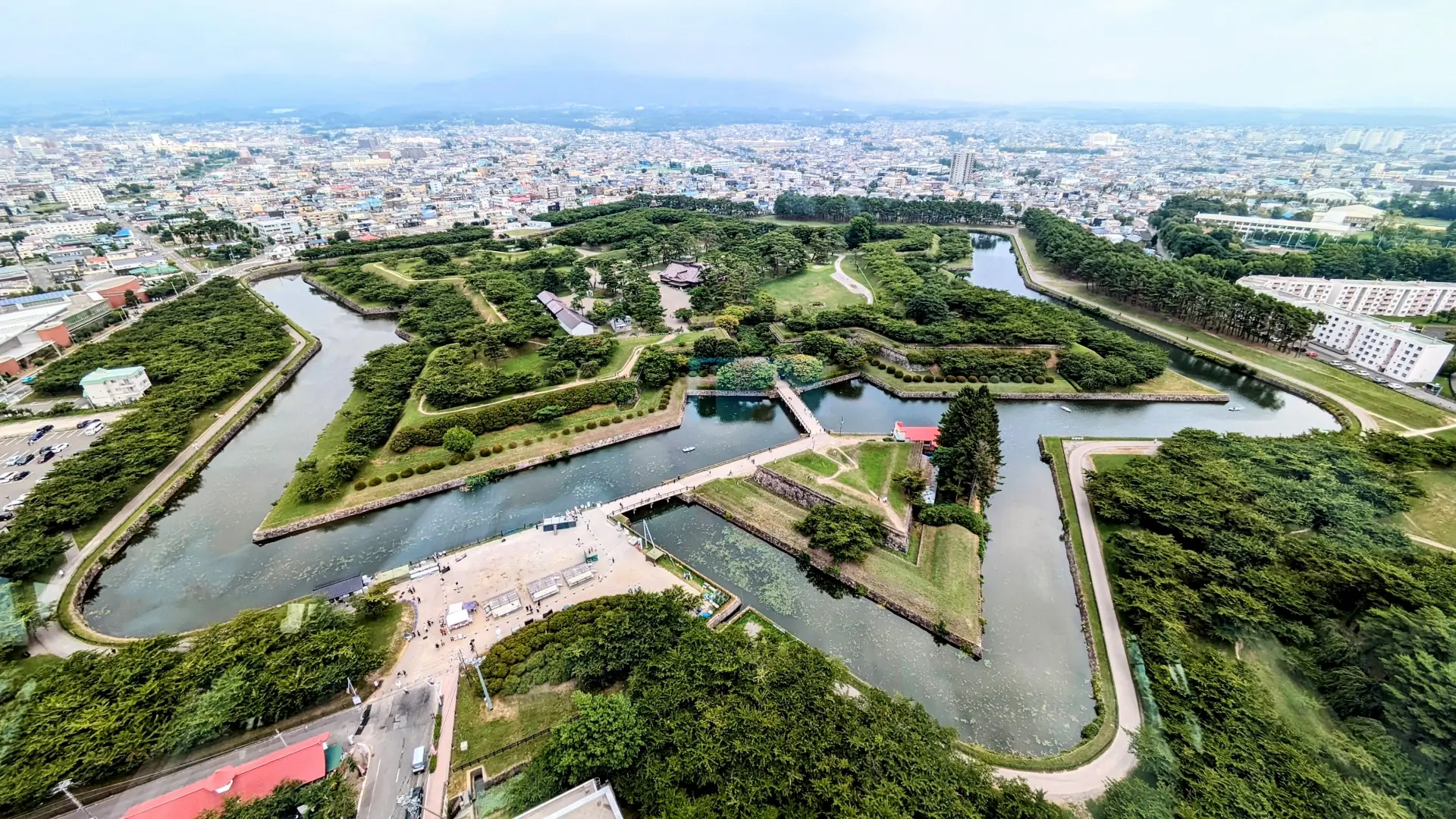 Aerial view of a star-shaped fort with a wide moat and green grounds, bordered by a city.
