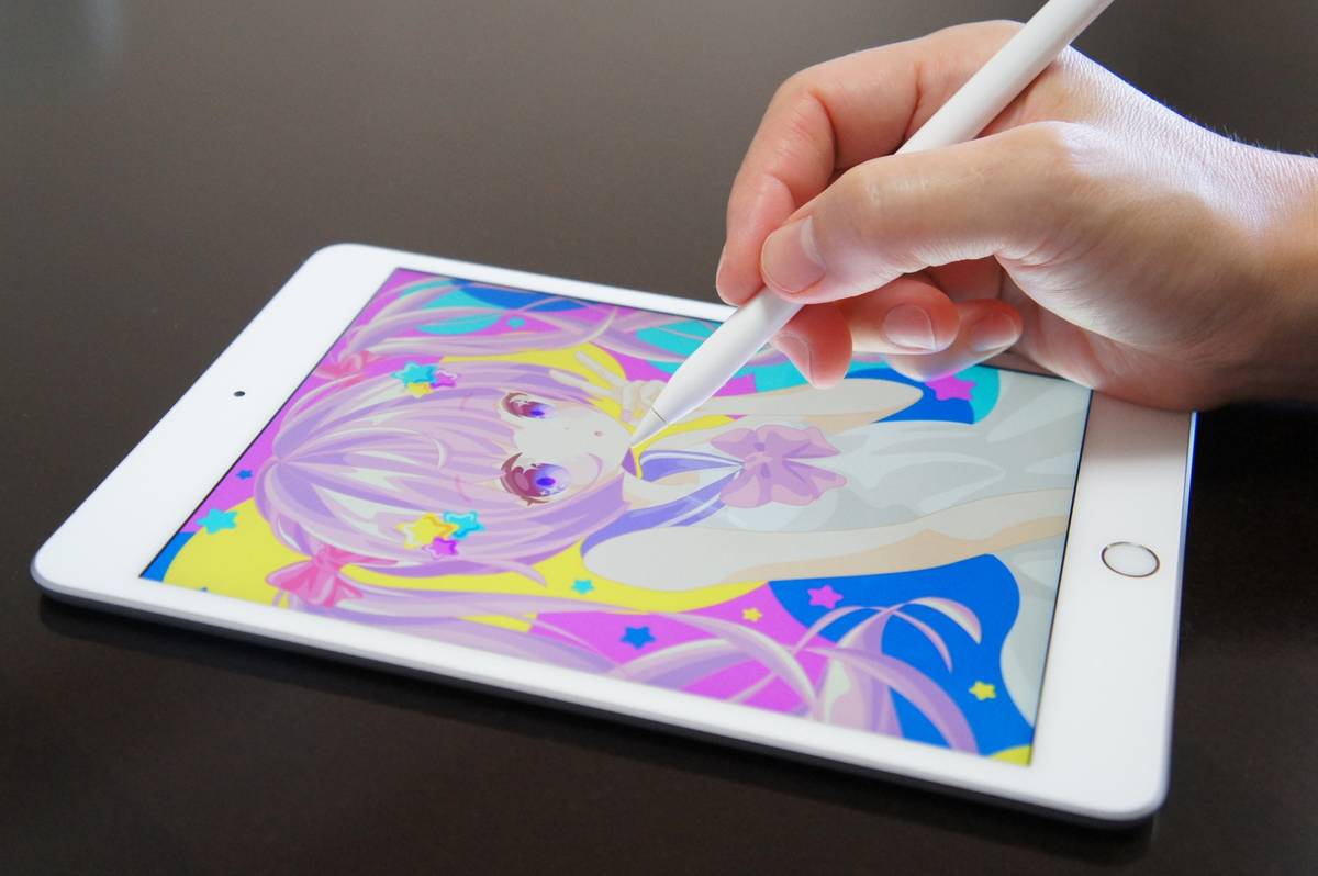 A hand uses a stylus to draw colorful anime art on a tablet.