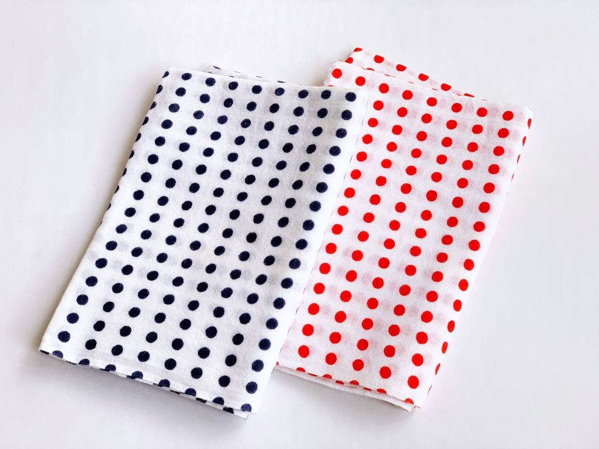Two folded white polka dot cloths, one with blue dots and one with red dots.