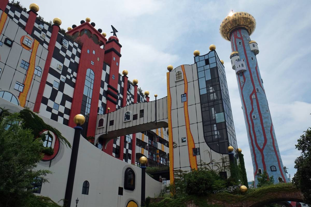 A whimsical and colorful building complex with a black and white checkerboard facade and a tall blue tower topped with a large golden dome.