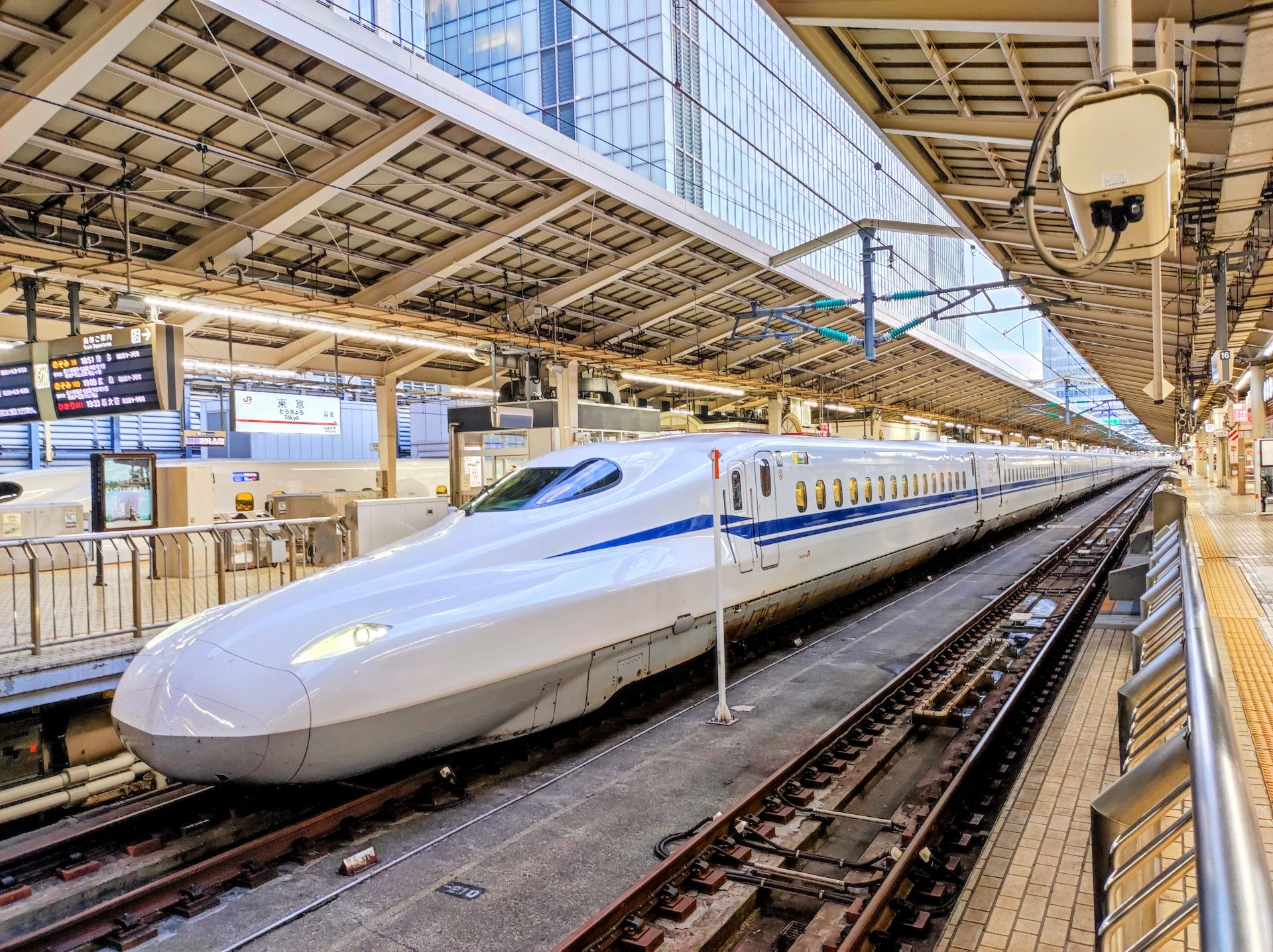 A white Shinkansen bullet train with blue stripes at a station platform.