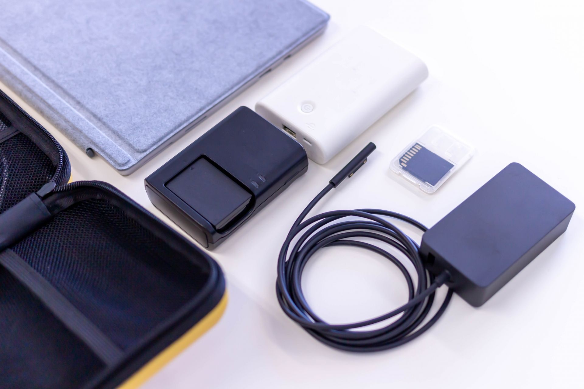 A collection of tech accessories, including a tablet cover, a portable SSD, a power bank, an SD card, a charger