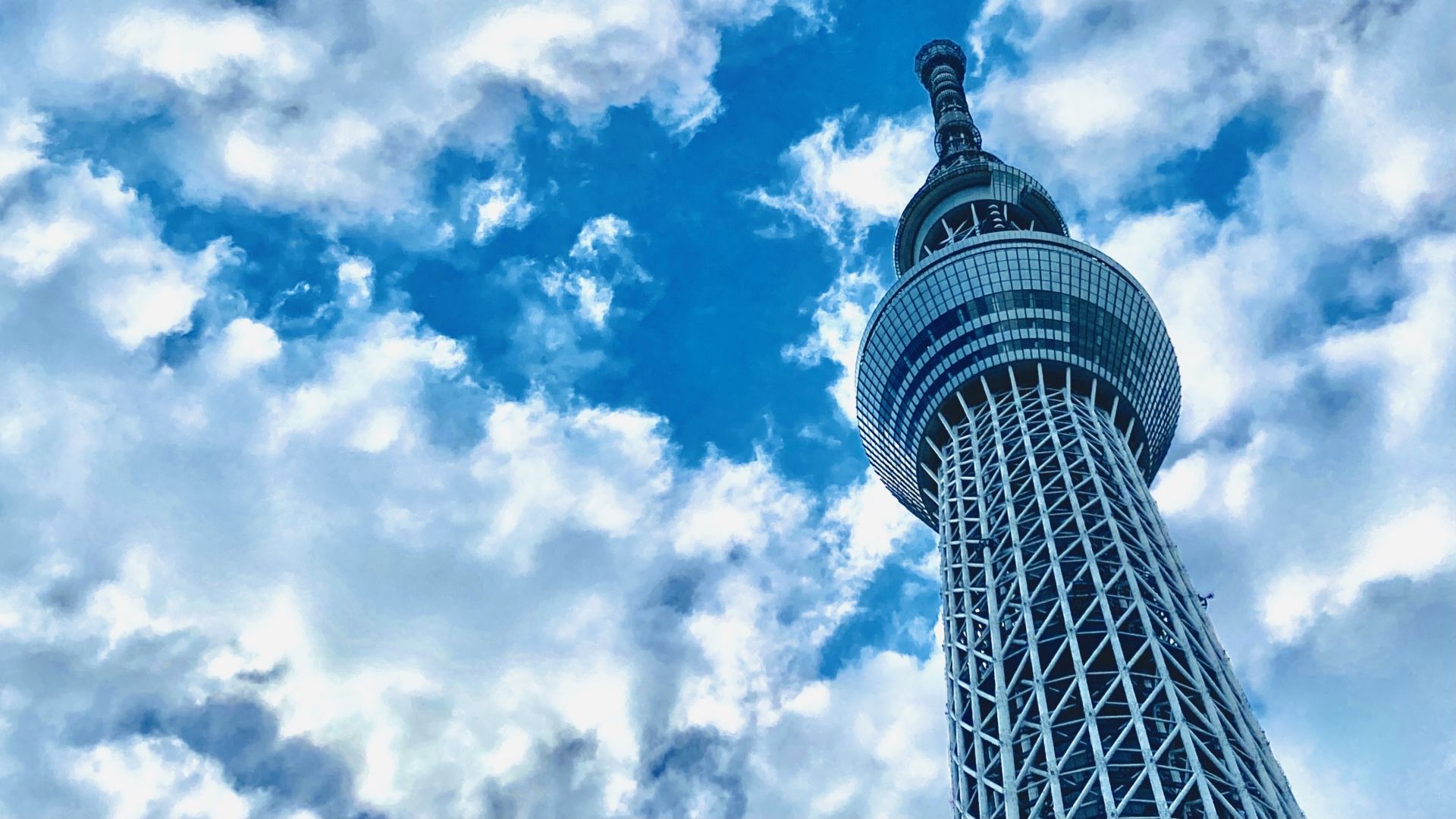 The Tokyo Skytree seen from below against a blue sky with white clouds.