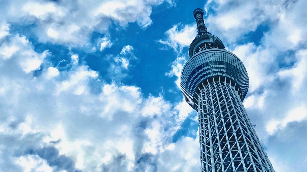 The Tokyo Skytree seen from below against a blue sky with white clouds.