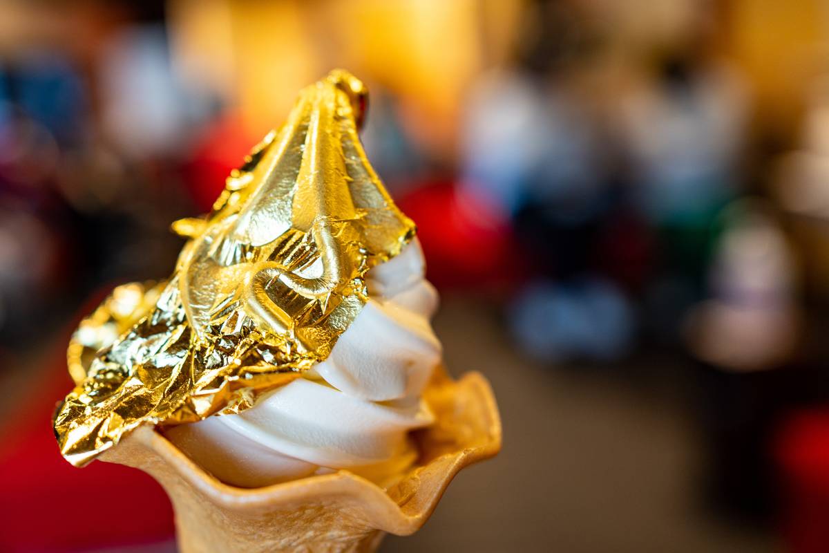 Soft-serve ice cream in a cone topped with gold leaf.
