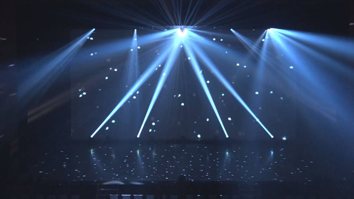 Stage illuminated by blue spotlights and scattered white lights.