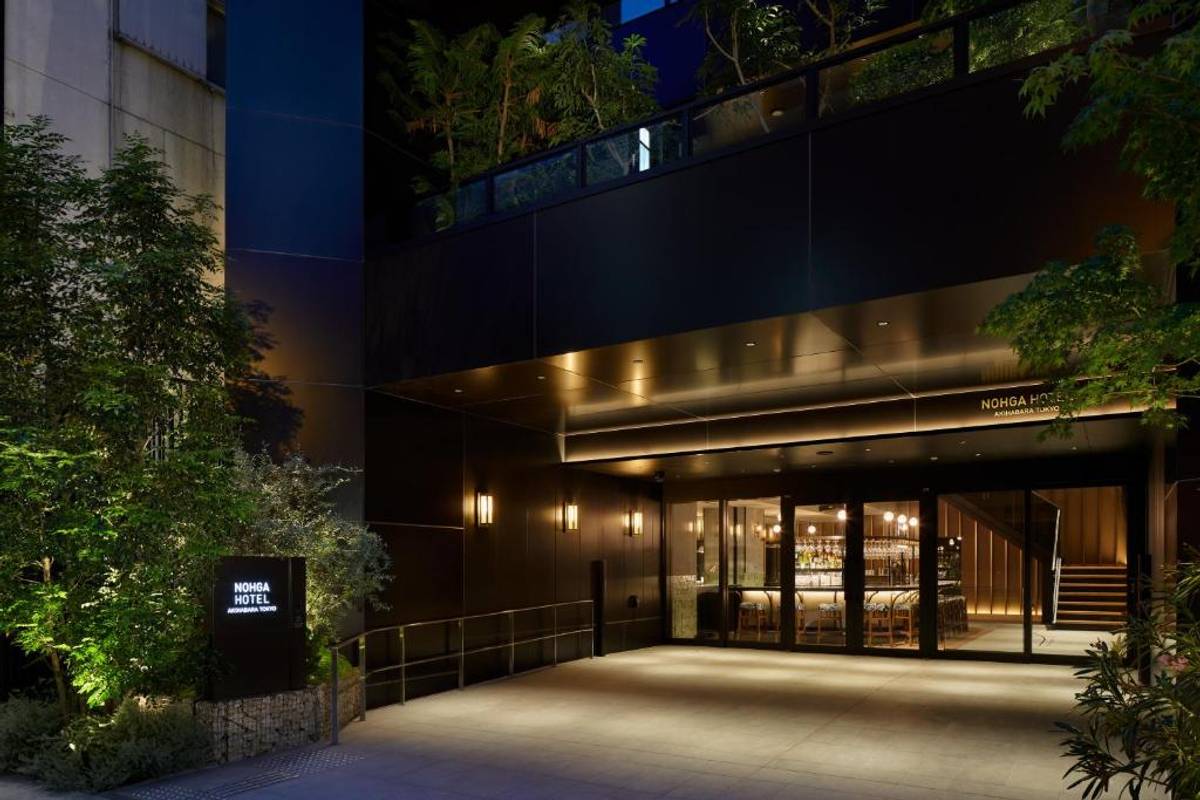 Night view of the modern NOHGA HOTEL exterior, with an illuminated entrance revealing a bar.