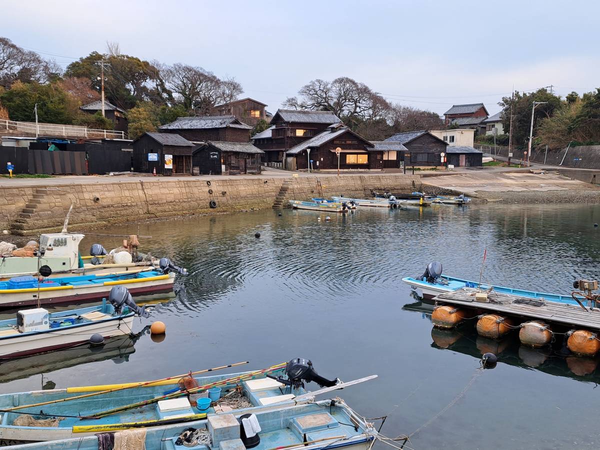 Fishing boats docked in a tranquil harbor with traditional wooden buildings on the shore.