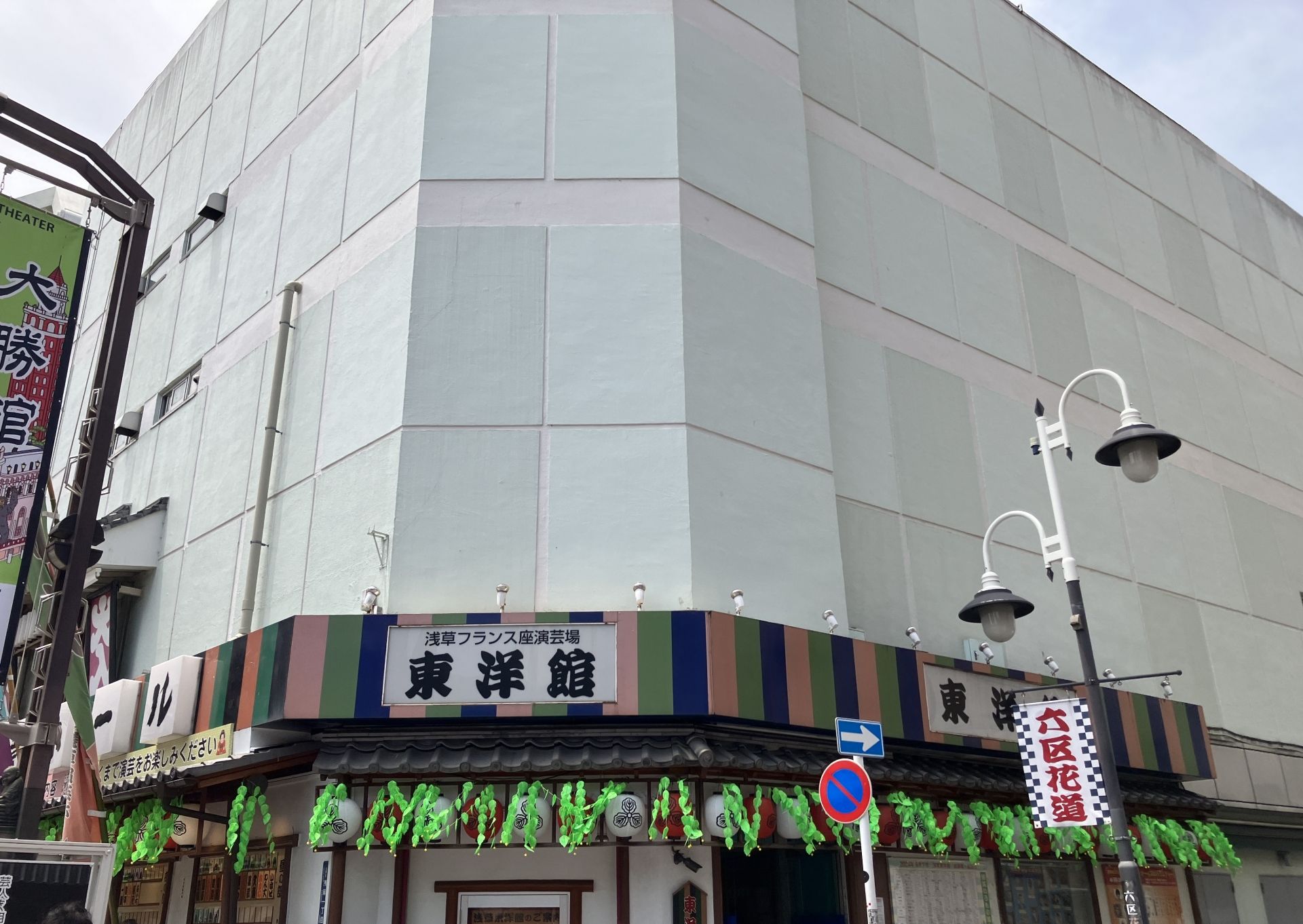Building with a striped awning, green garlands, and Japanese text reading "東洋館" on its lower level.