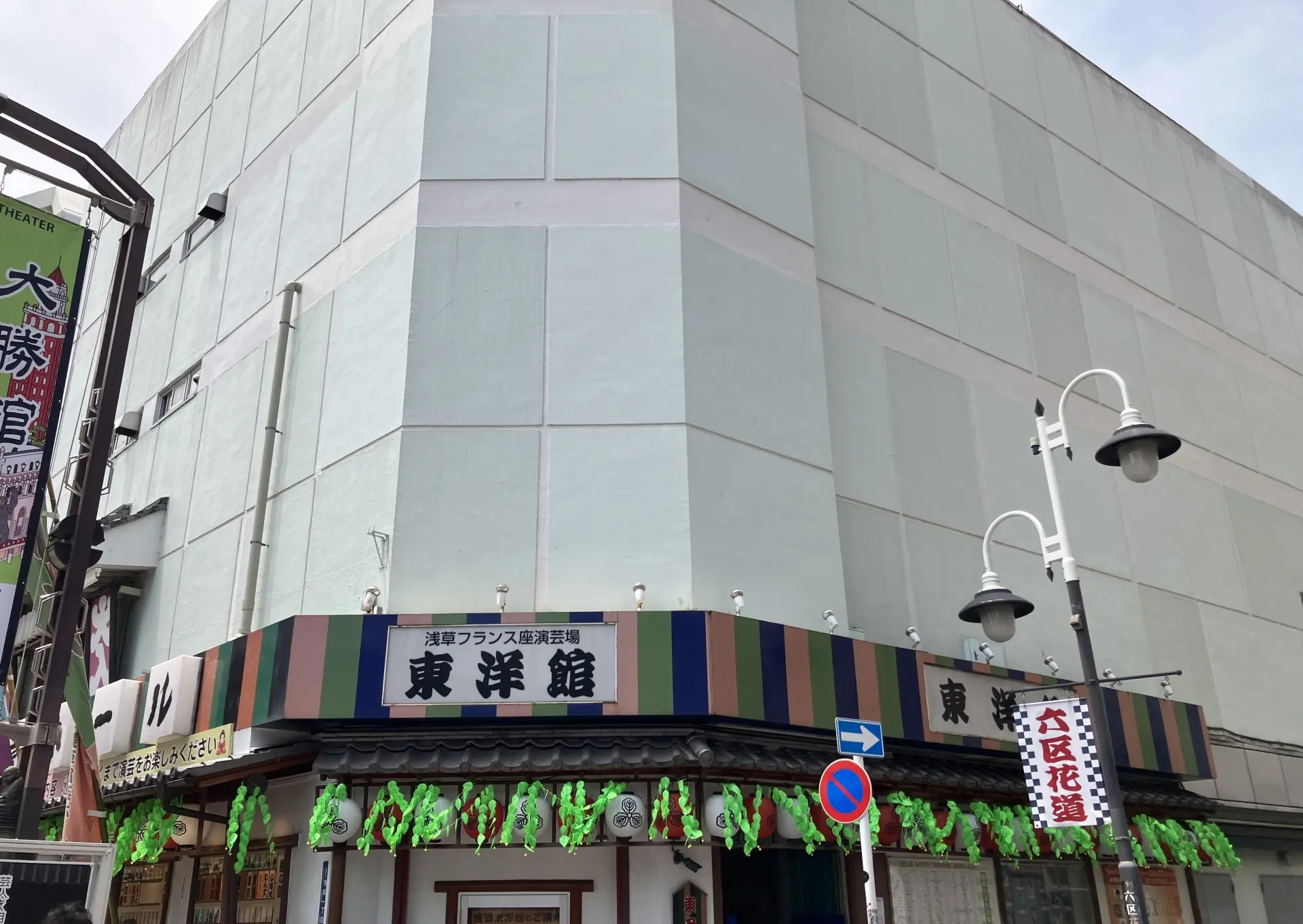Building with a striped awning, green garlands, and Japanese text reading "東洋館" on its lower level.