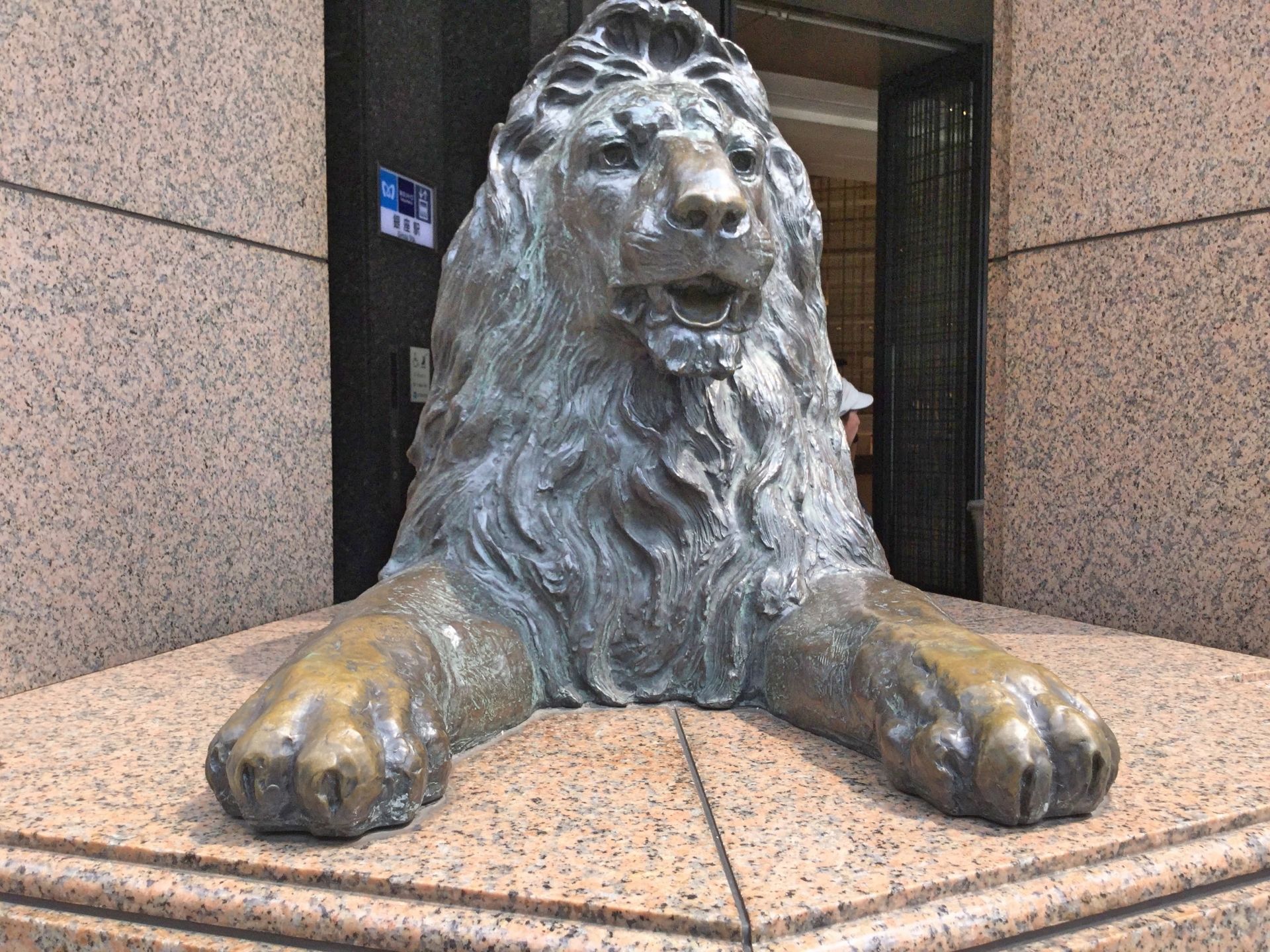 Bronze statue of a lion lying with an open mouth on a granite base.