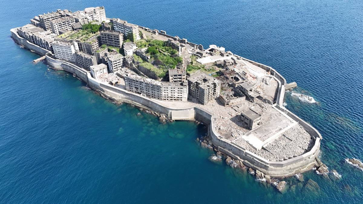 Aerial view of Hashima Island, an abandoned island densely packed with crumbling concrete buildings.