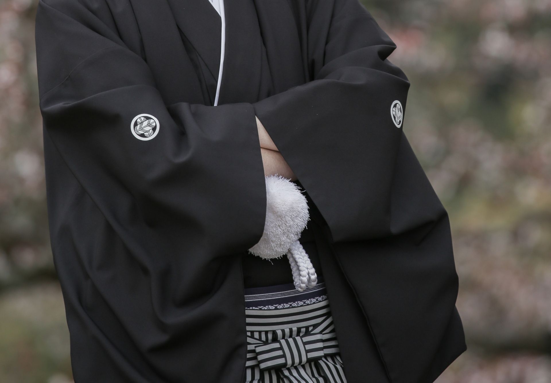 a man in a black kimono is standing with his arms crossed